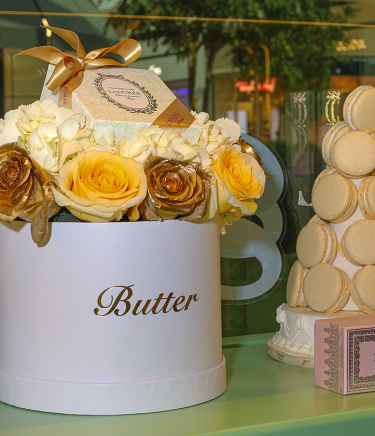 Elegant Butter Chérie gift set featuring a matte white hat box filled with 24K gold-dusted and white roses, alongside Ladurée’s Arabesque Box of assorted gluten-free macarons.
Elegant Butter Chérie gift set featuring a matte white hat box filled with 24K gold-dusted and white roses, alongside Ladurée’s Arabesque Box of assorted gluten-free macarons.