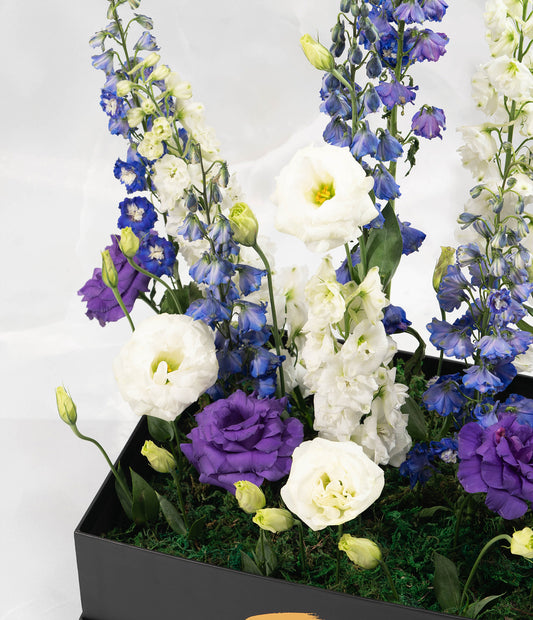 A detailed close-up focusing on the interplay between the spiky delphinium blooms and the softer lisianthus flowers, capturing rich texture and tonal subtlety.