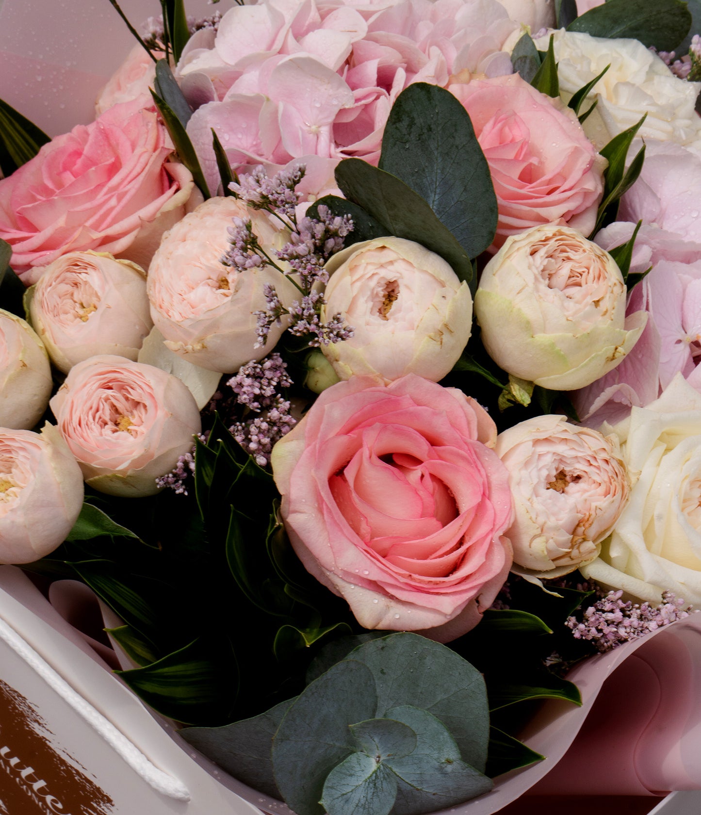 A tight detail of the floral composition, emphasizing the pastel pinks and creamy whites.