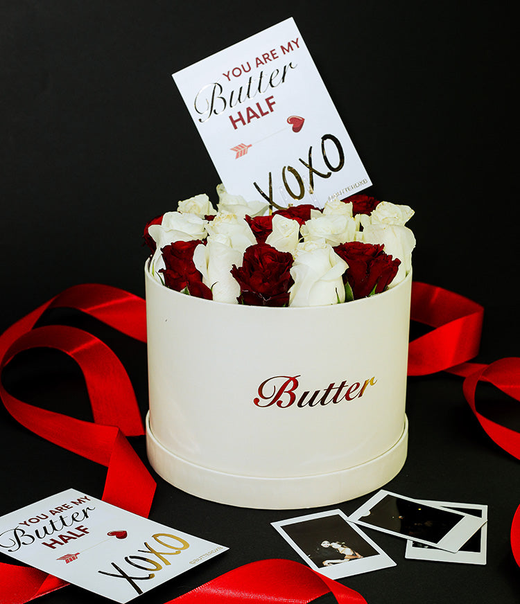A soft beige hat box featuring the word ‘BUTTER’ holds a stunning mix of red and white roses, paired with a gold-foiled card that reads “You are my BUTTER half” followed by a sweet xoxo kiss.