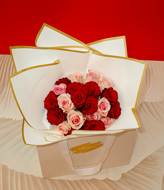 A bouquet of red and pink roses in a paper wrap, presented on a red background.