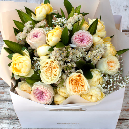 Butter Charm bouquet featuring bright yellow blooms arranged in a matte white Butter branded bag - warm, subtle, and beautiful.